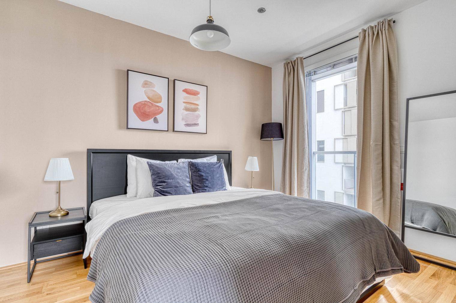 Schlafzimmer mit Doppelbett, Nachttischen und Blick auf die Gebäude.