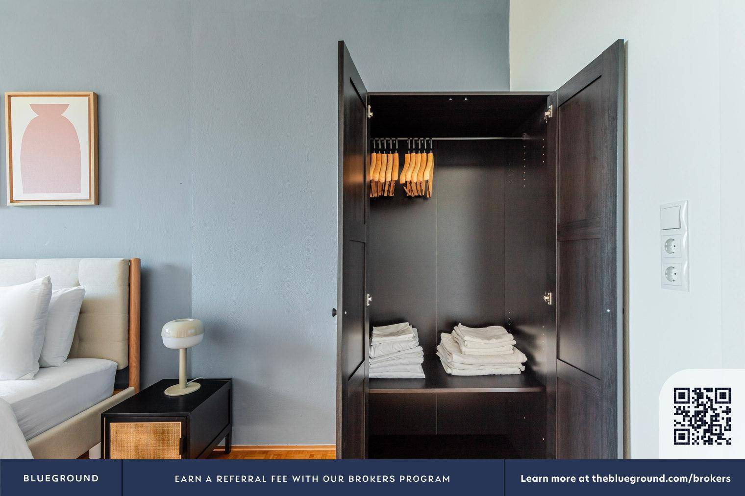 Offener Kleiderschrank mit Kleiderbügeln und gestapelten Handtüchern im Schlafzimmer.