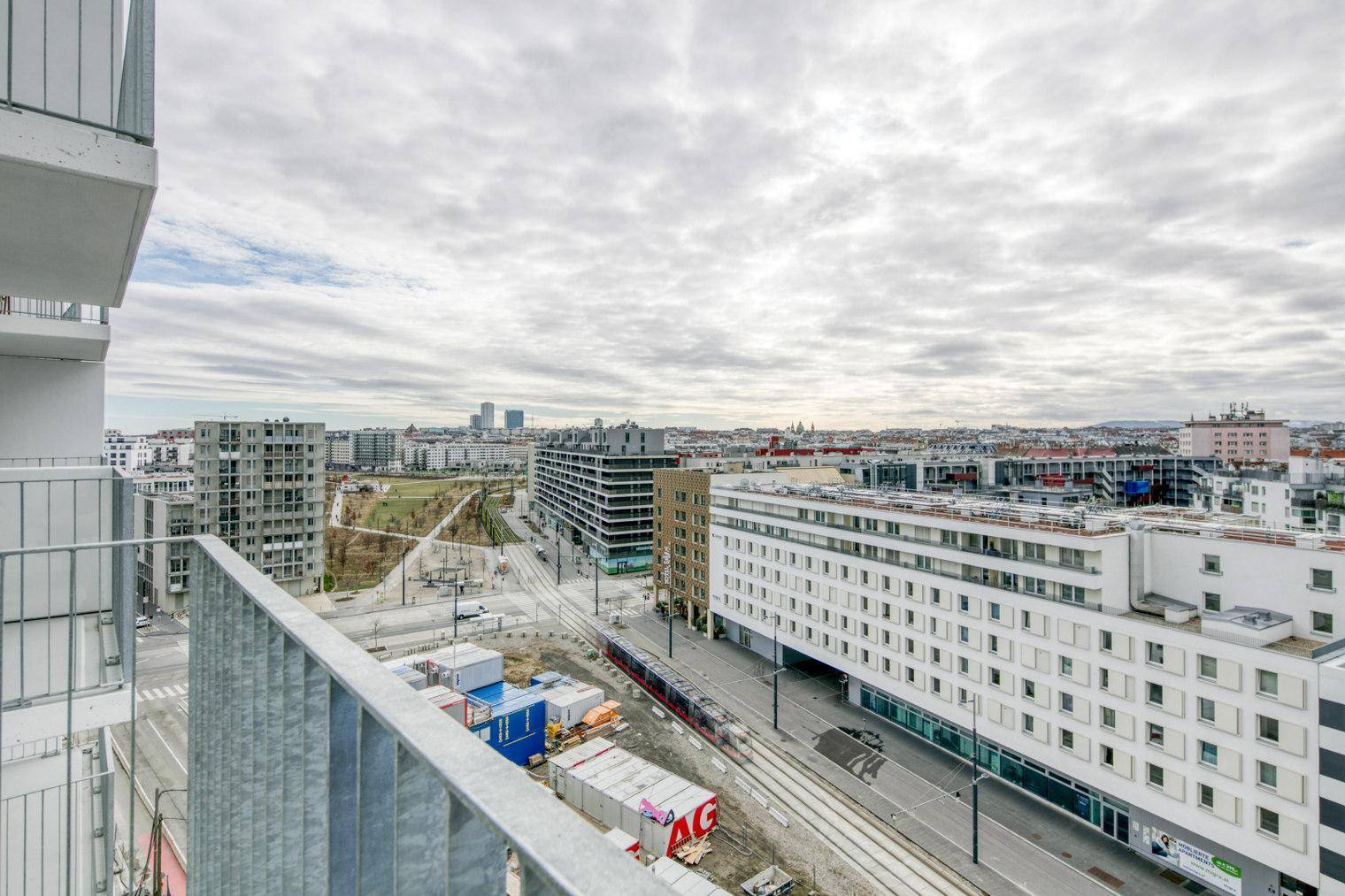 Weitläufiger Stadtblick von einem Balkon, zeigt moderne Gebäude und Infrastruktur.