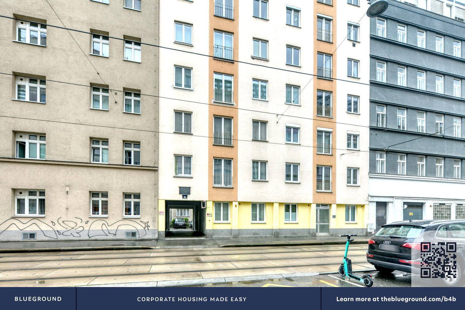 Straßenansicht von Mehrfamilienhäusern mit Balkonen und einem geparkten Auto.