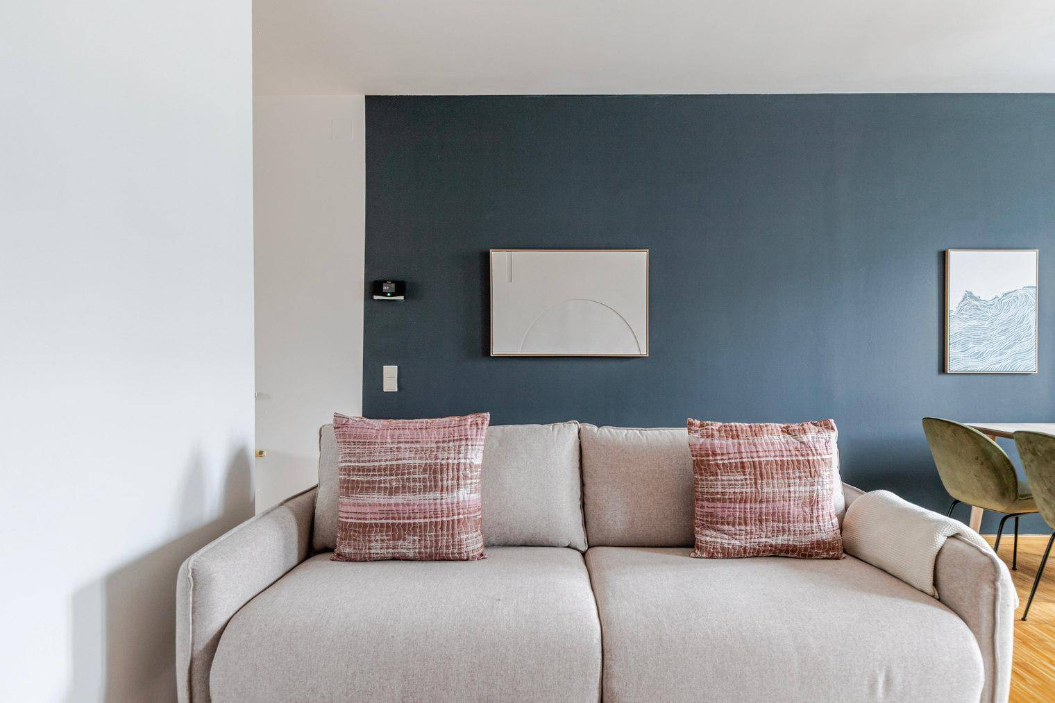 Gemütliches Sofa vor einer stilvollen dunkelblauen Akzentwand im Wohnbereich.