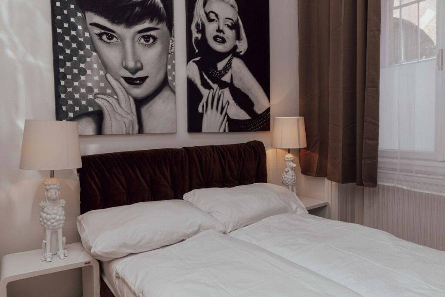 Gemütliches Schlafzimmer mit Doppelbett, Nachttischen und auffälligen Pop-Art-Bildern an der Wand.