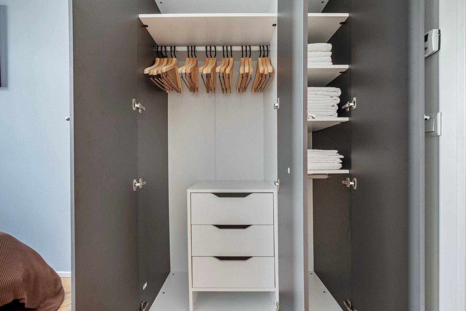 Geräumiger Kleiderschrank mit Kleiderbügeln, Schubladen und gefalteter Wäsche.