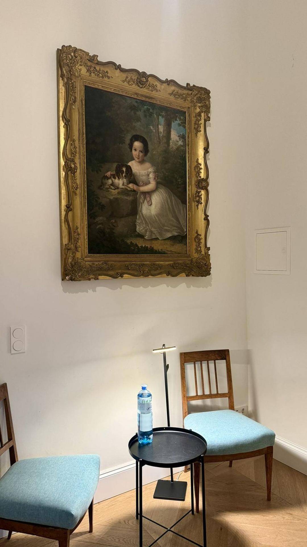 Elegante Sitzecke mit zwei Stühlen und einem großen, gerahmten Gemälde an der Wand.