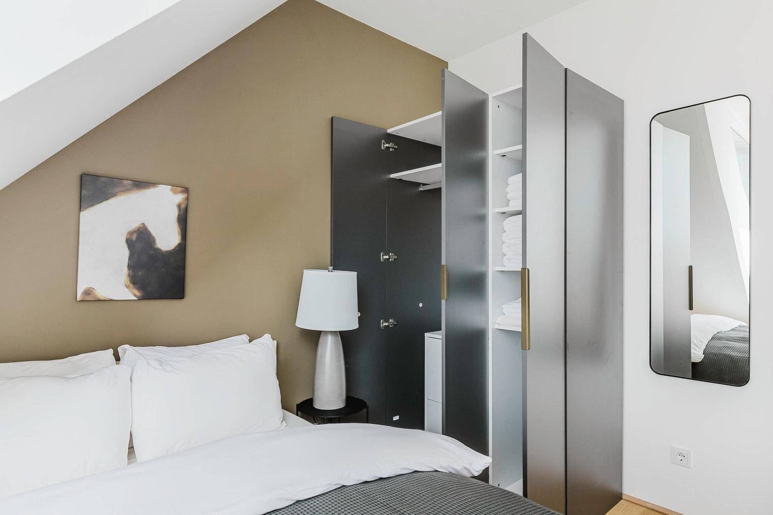 Schlafzimmer mit integriertem Kleiderschrank und einem modernen Spiegel, ergänzt durch eine Akzentwand.