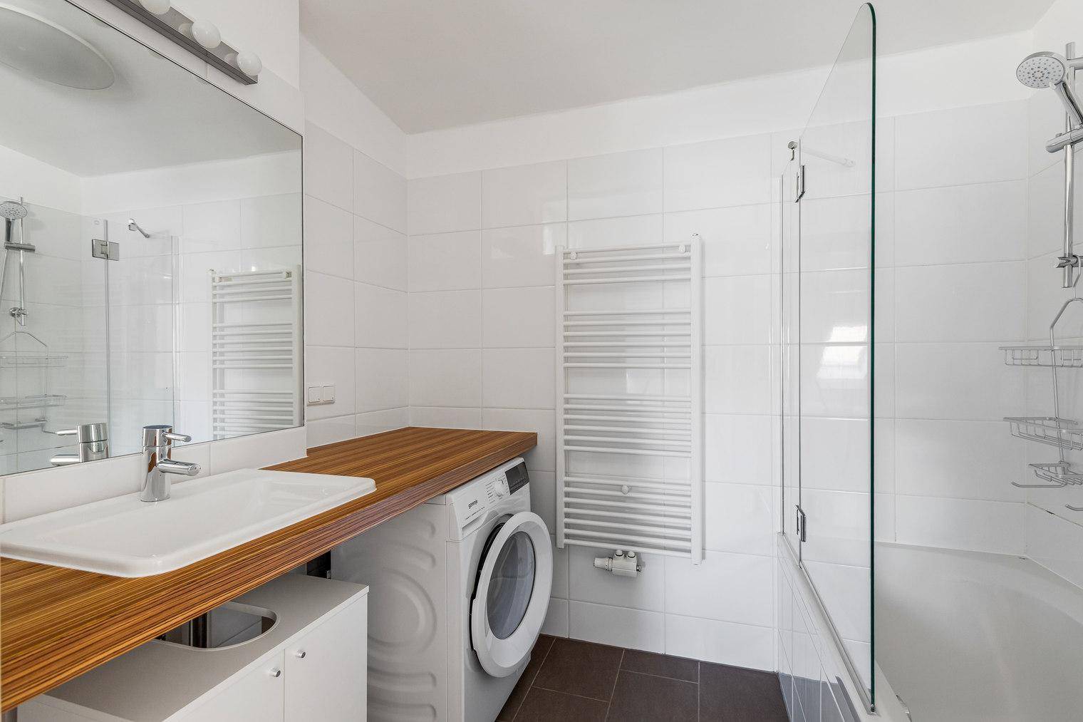 Modernes Badezimmer mit Badewanne, Dusche, Waschbecken und Waschmaschine.