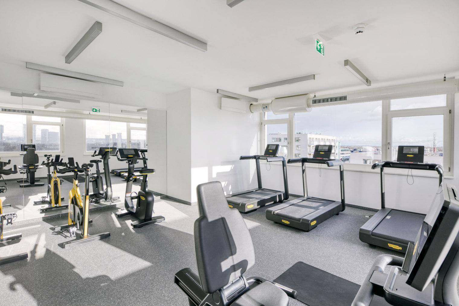 Gut ausgestatteter Fitnessraum mit Laufbändern und Fahrrädern, ideal für Sportbegeisterte.