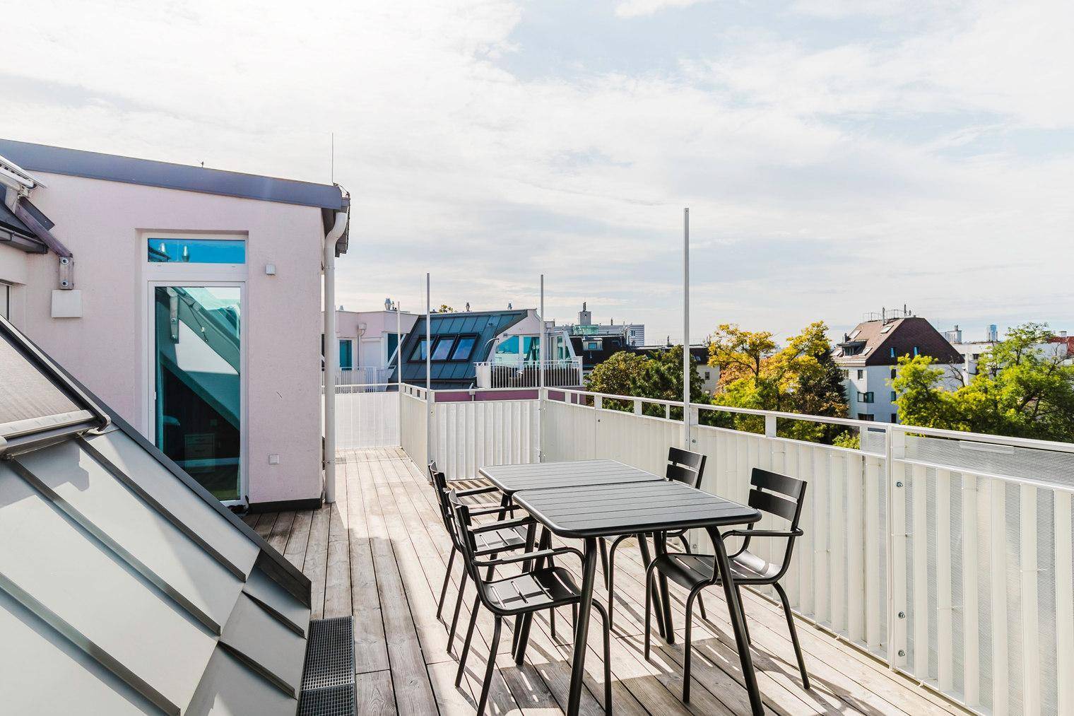 Sonnige Dachterrasse mit Holzboden und Sitzgelegenheiten, ideal für entspannte Stunden im Freien.