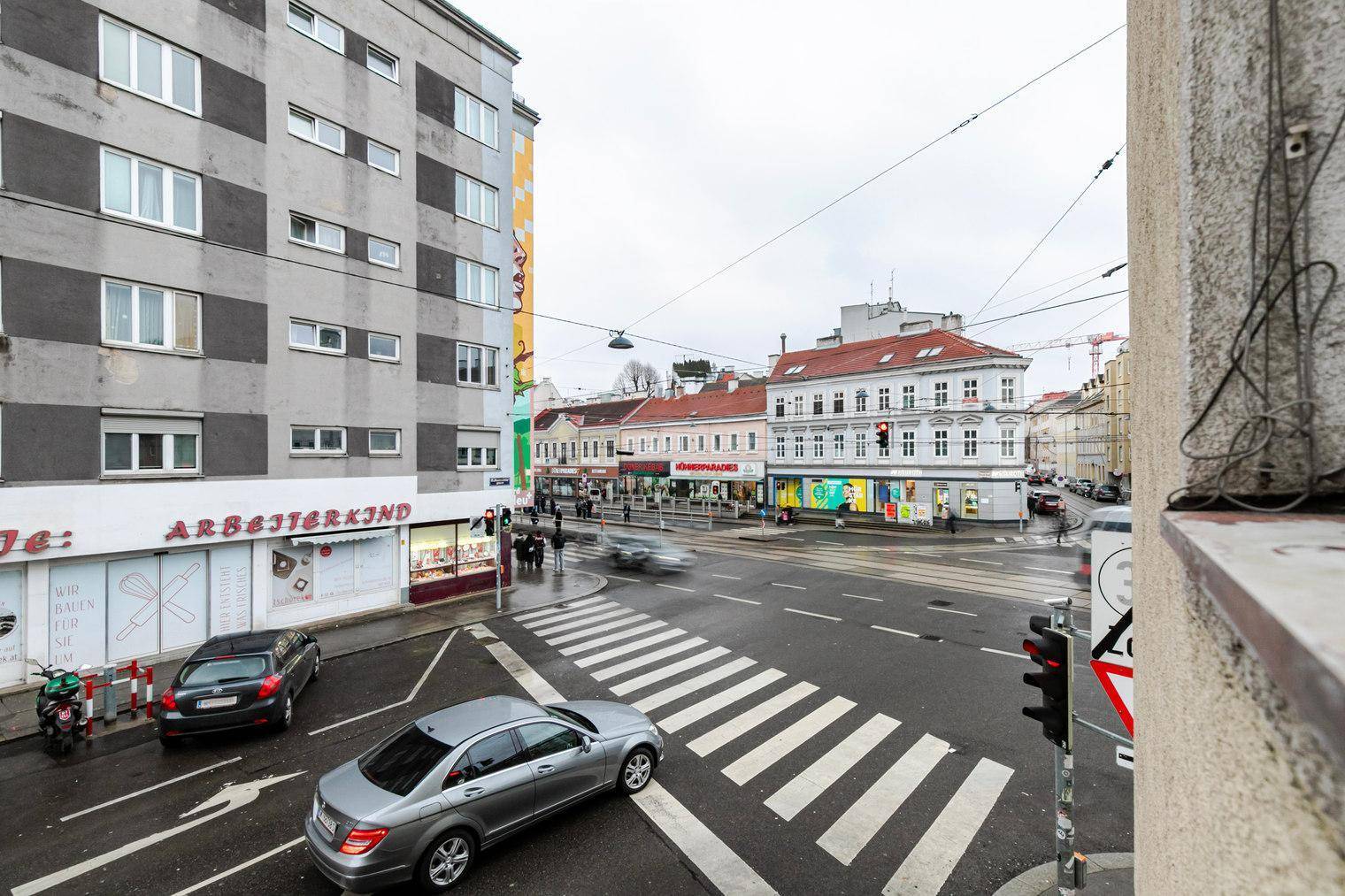 Weitläufiger Blick auf eine städtische Straße mit Fußgängerüberweg und umliegenden Gebäuden.