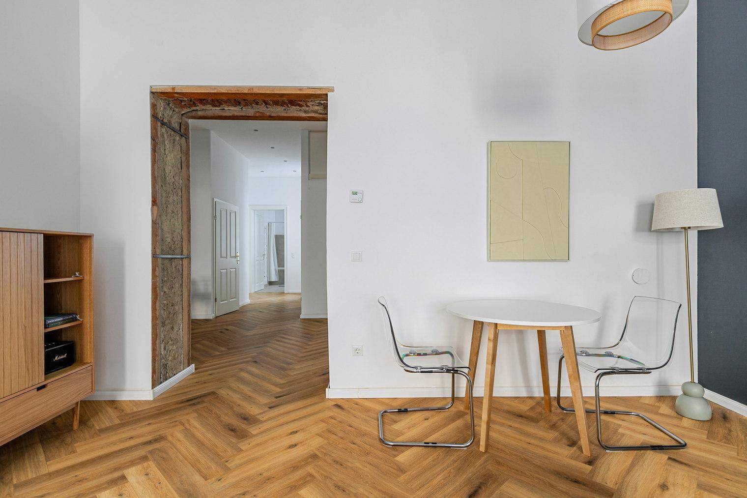 Essbereich im Wohnzimmer mit kleinem Tisch, transparenten Stühlen und Blick in den Flur.