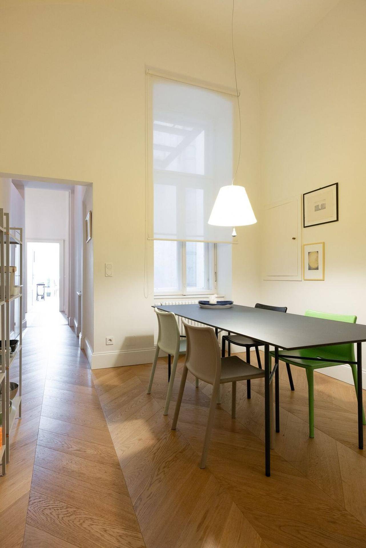 Geräumiger Essbereich mit Fischgrätparkett, modernem Esstisch und hoher Decke.