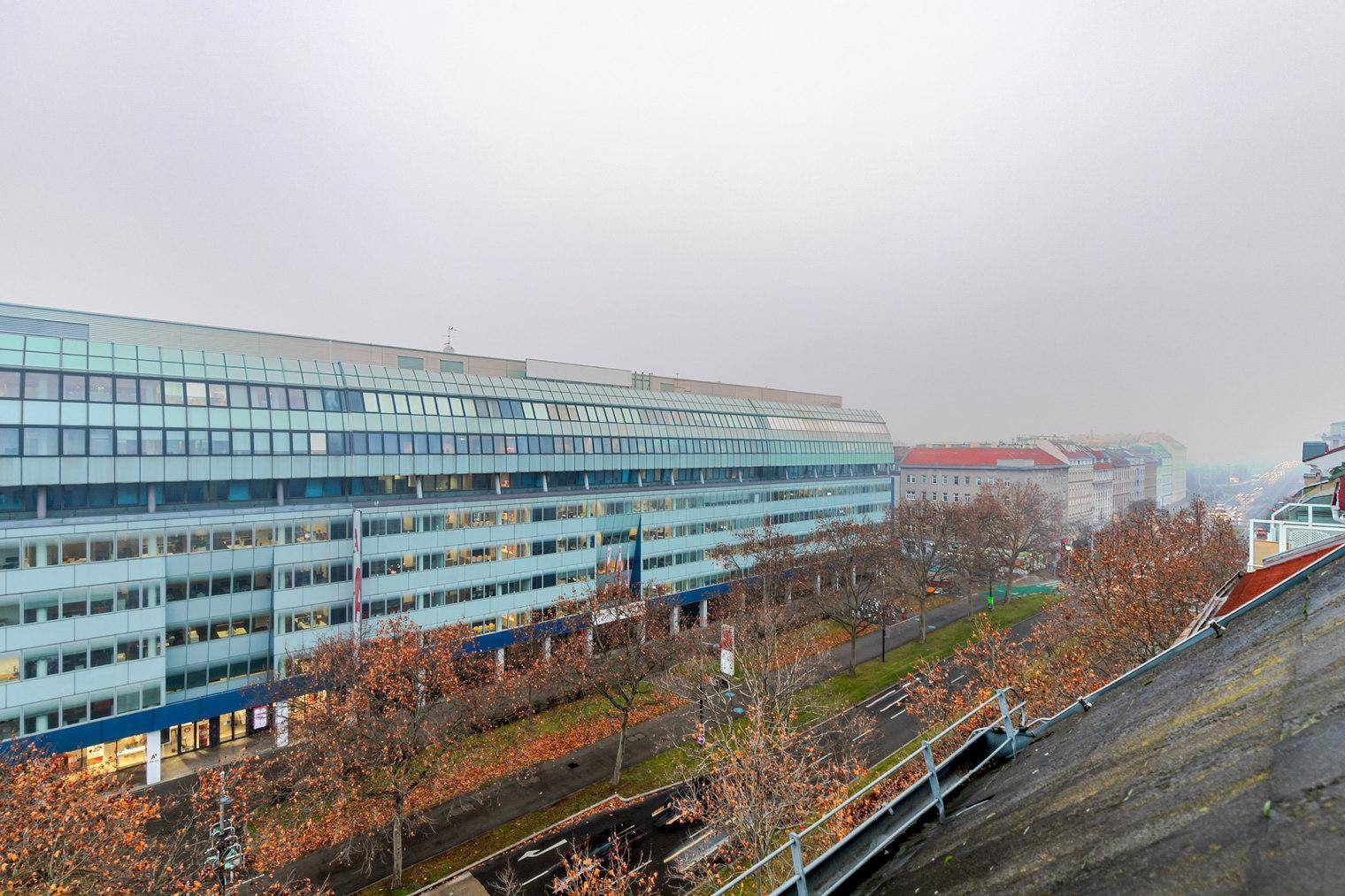 Weitläufiger Blick auf moderne Bürogebäude und eine belebte Straße an einem trüben Tag.