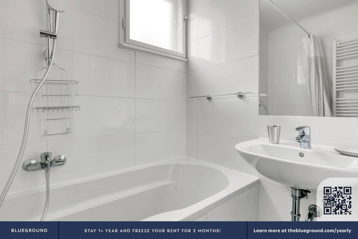 Helles Badezimmer mit Badewanne, Duscharmatur, Waschbecken und Fenster.