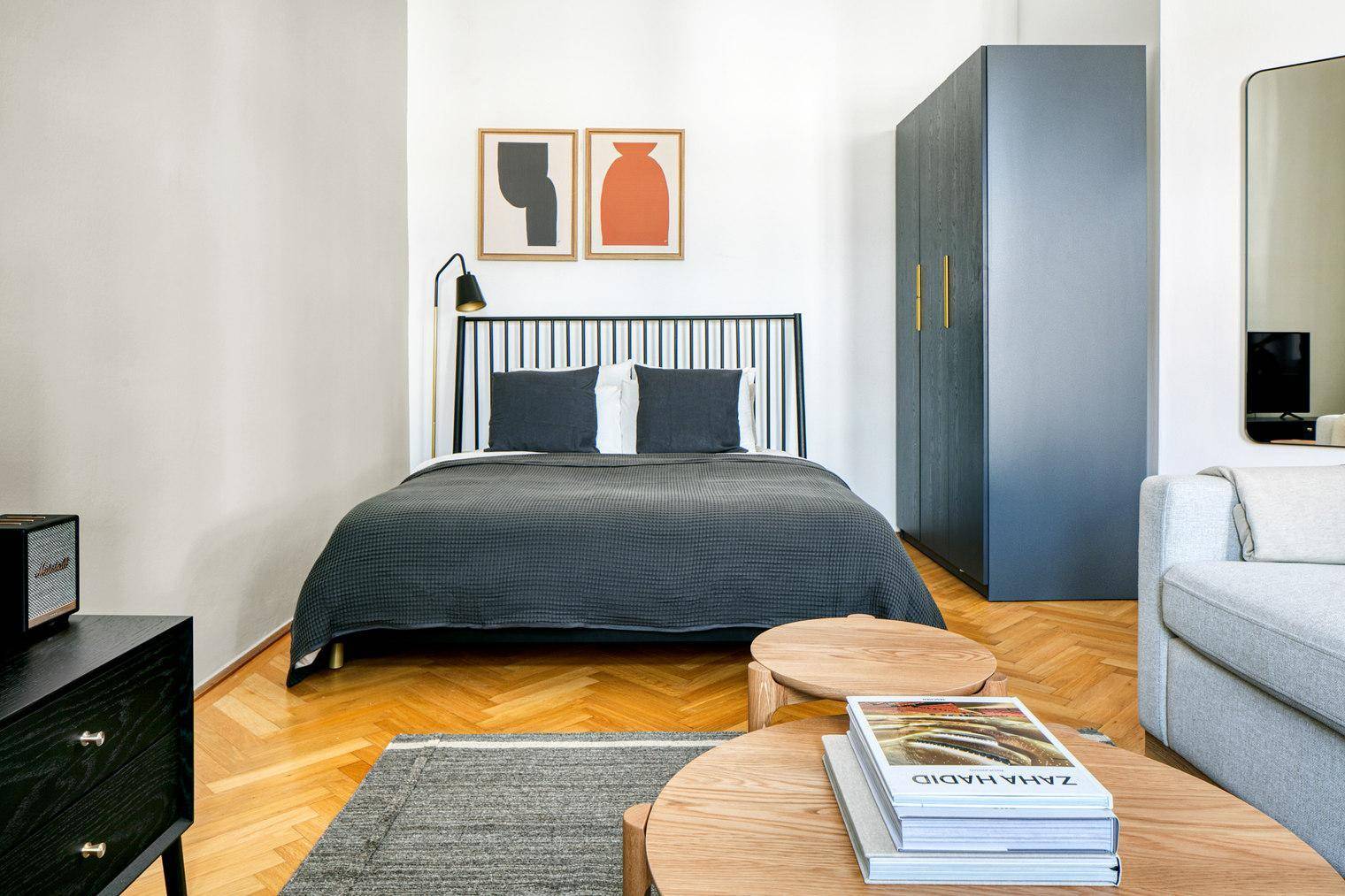 Modernes Schlafzimmer mit Doppelbett, Holzboden und dunklem Kleiderschrank.