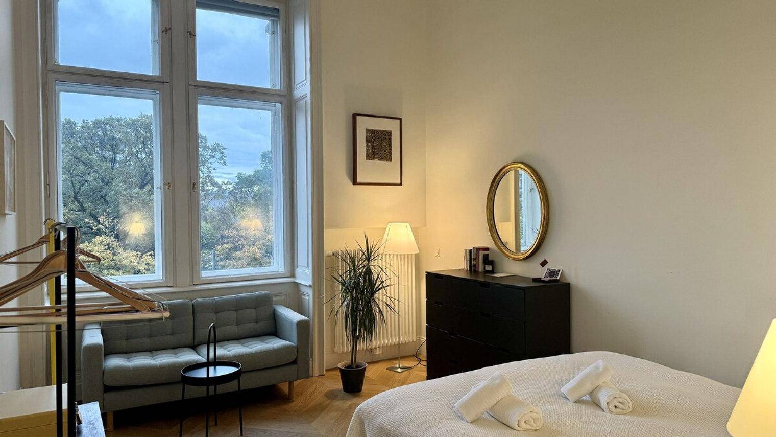 Geräumiges Schlafzimmer mit Doppelbett, Sofa und großen Fenstern mit Blick auf die Umgebung.
