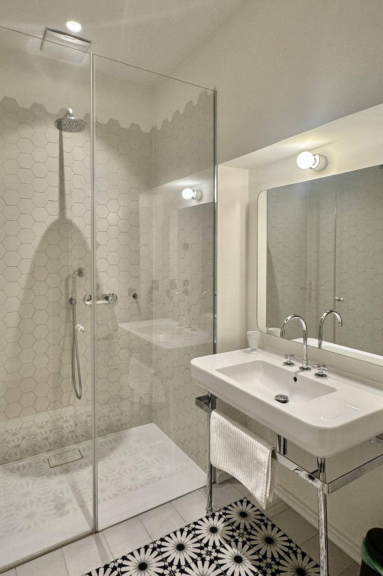 Modernes Badezimmer mit großer begehbarer Dusche, stilvollen Fliesen und minimalistischem Design.