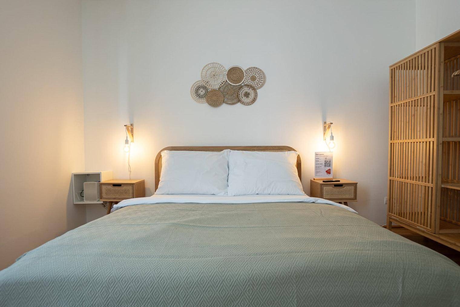 Schlafzimmer mit Doppelbett, Nachttischen und dekorativer Wandkunst in heller Umgebung.