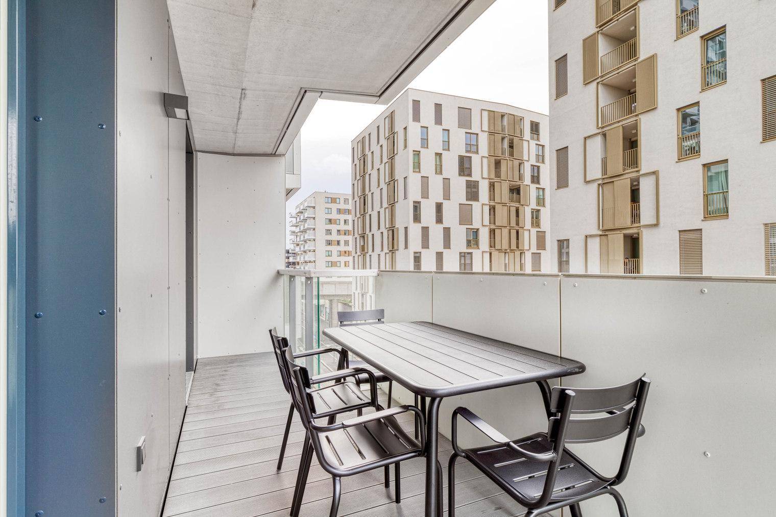 Balkon mit Sitzgelegenheiten und Blick auf moderne Wohngebäude.
