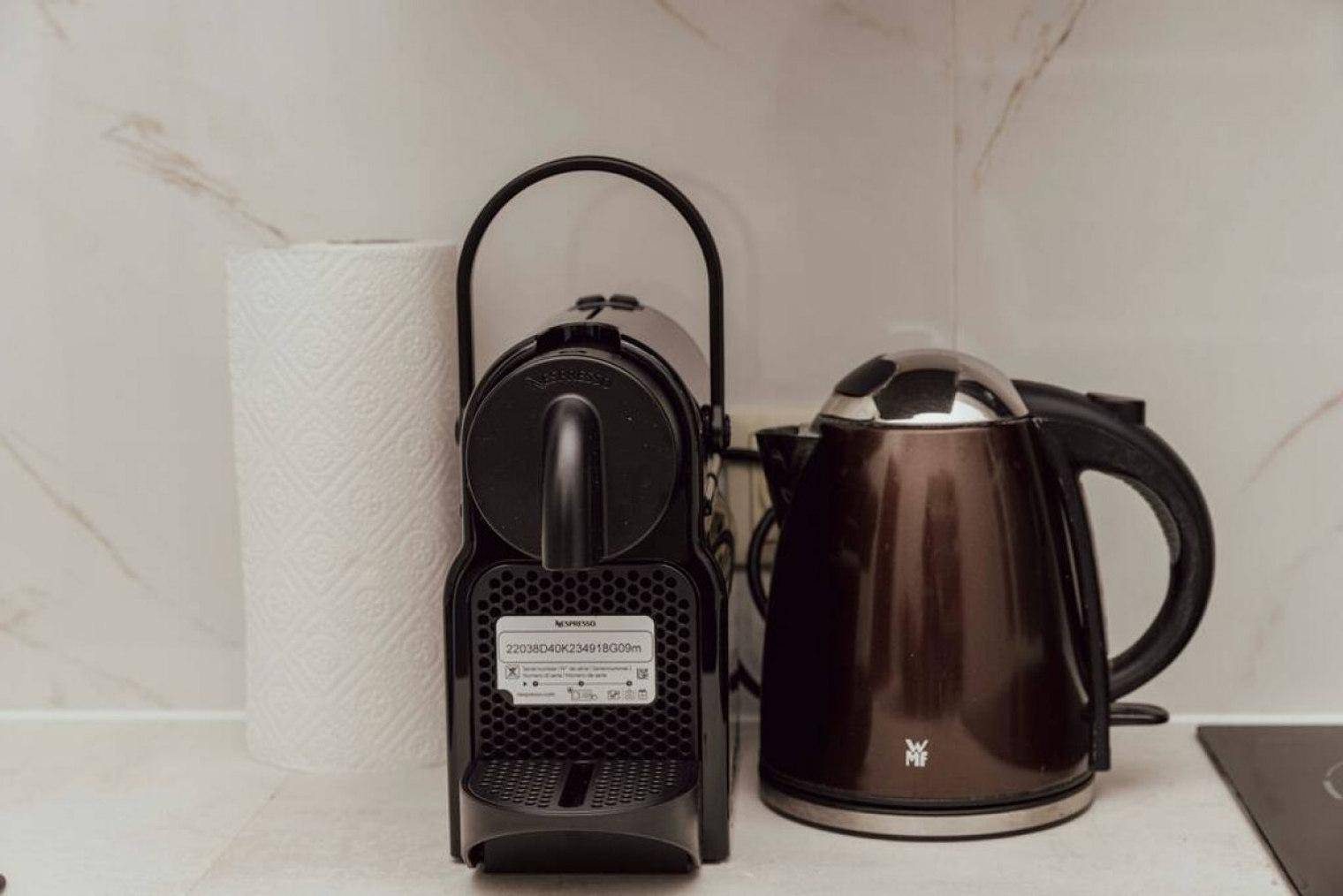 Detailansicht einer Kaffeemaschine und eines Wasserkochers auf der Küchenarbeitsplatte.
