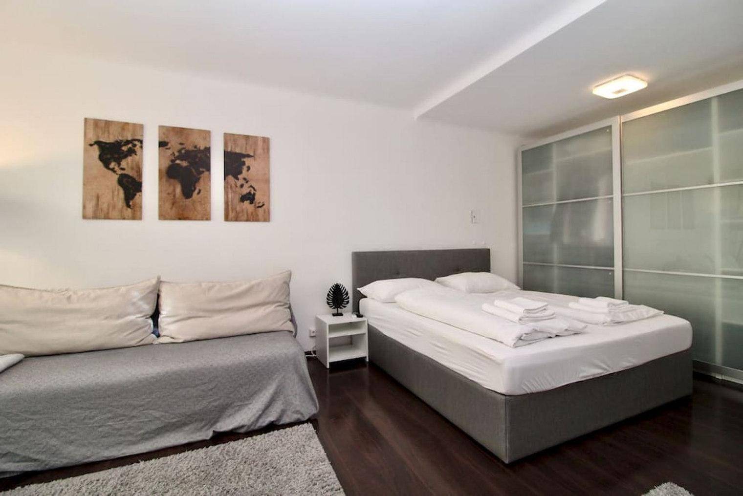 Kombinierter Wohn- und Schlafbereich mit Sofa, Doppelbett und großem Schiebetürenschrank.