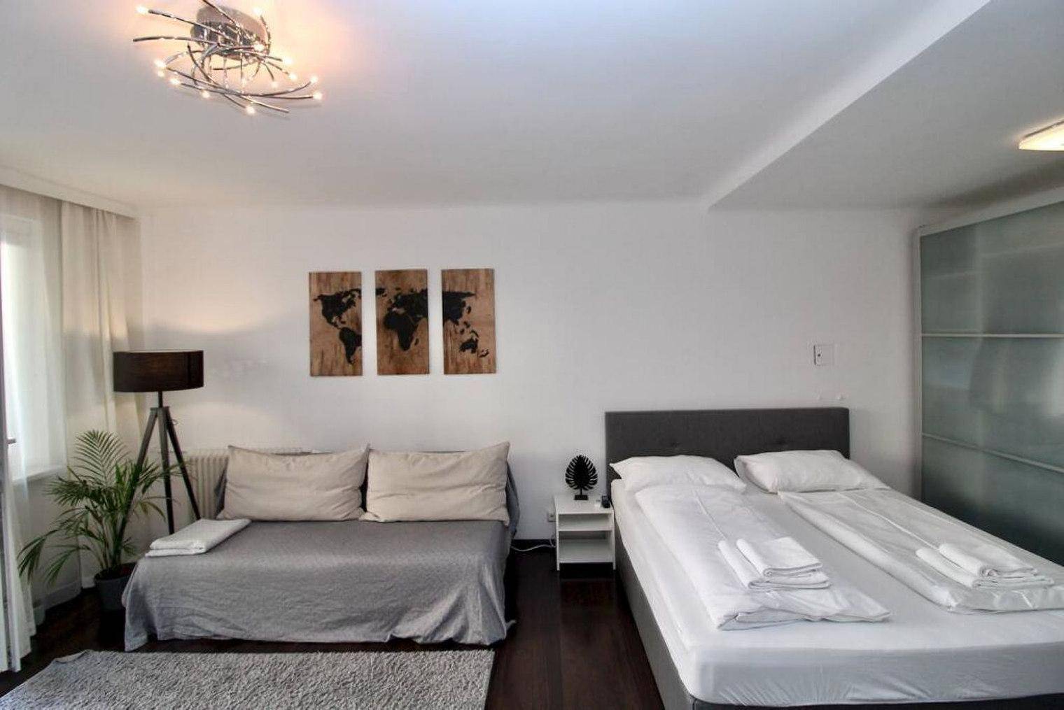 Kombinierter Wohn- und Schlafbereich mit Sofa, Doppelbett und großem Schiebetürenschrank.