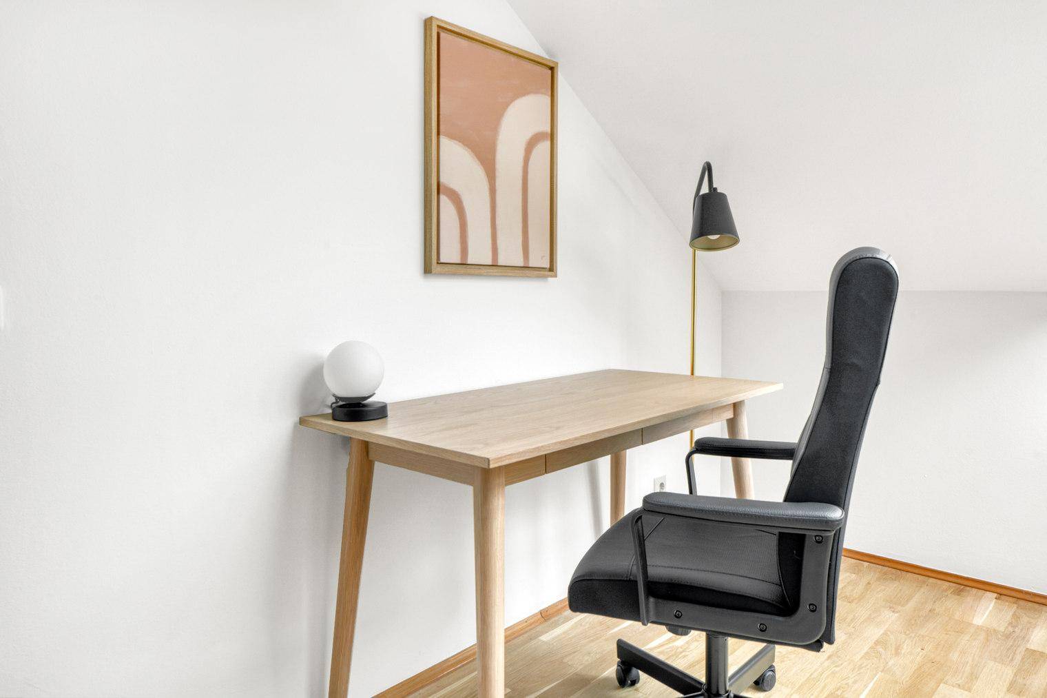 Heller Arbeitsbereich mit Holzschreibtisch, Bürostuhl und moderner Wandkunst.