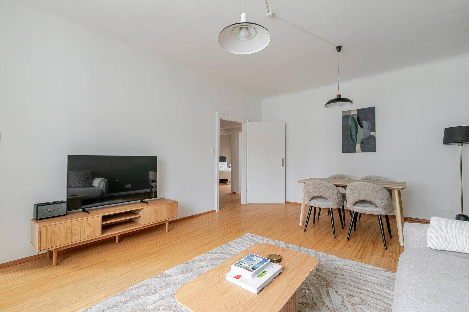 Offener Wohn- und Essbereich mit Holzboden, Fernseher und modernem Esstisch.