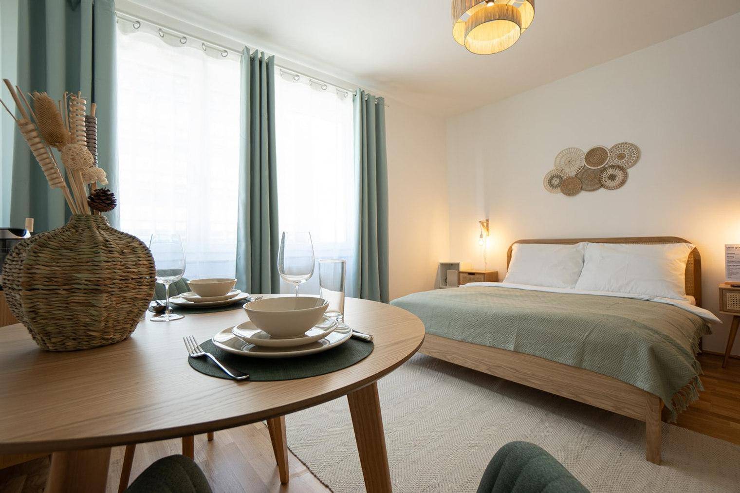 Esstisch im Schlafzimmer mit Geschirr und Blick auf das Doppelbett, ideal für kleine Mahlzeiten.