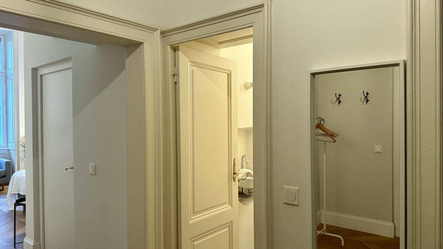 Heller Flur mit mehreren Türen und einem Garderobenspiegel.