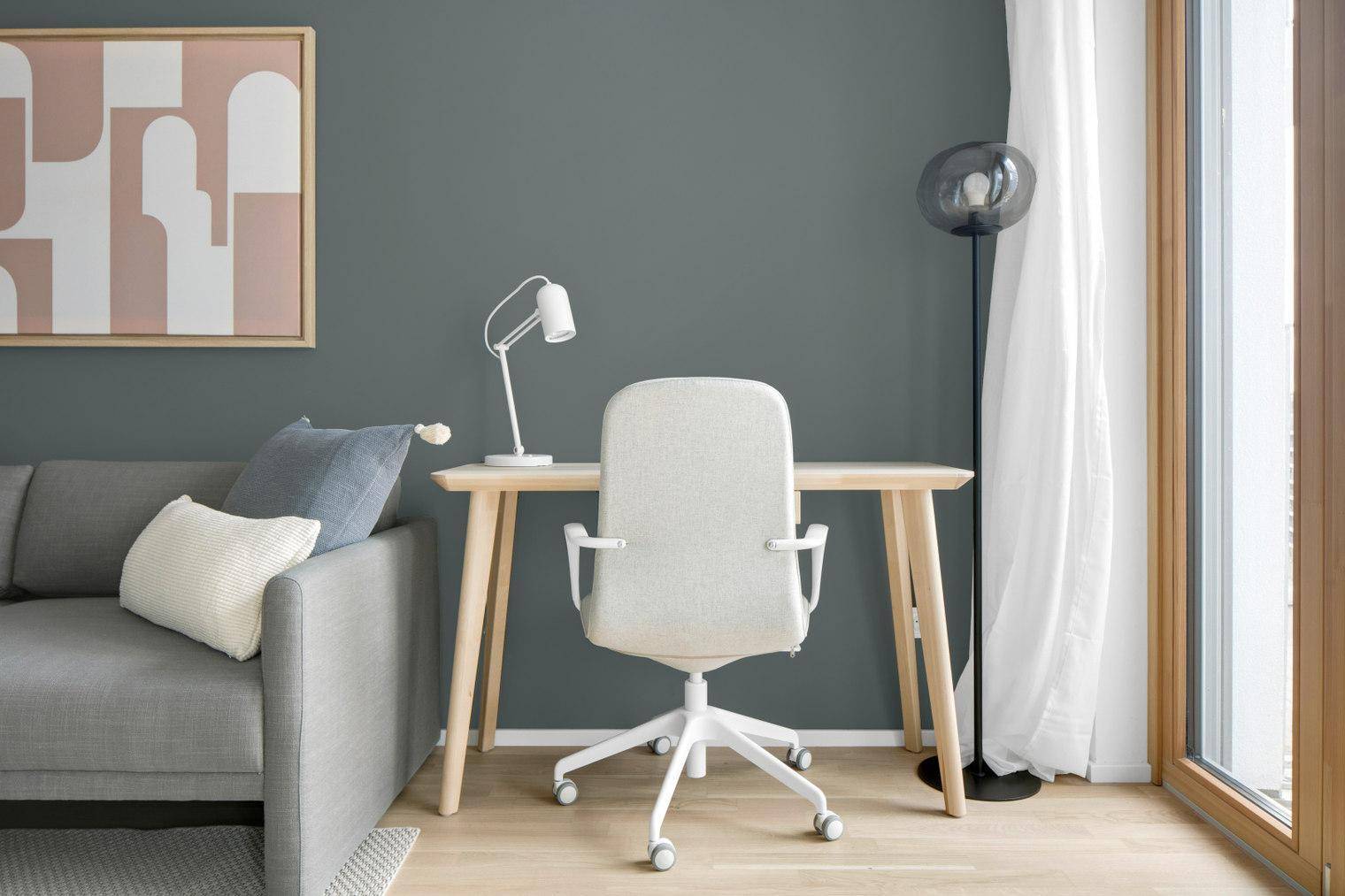 Heller Arbeitsbereich mit Schreibtisch, Bürostuhl und großem Fenster im Wohnbereich.