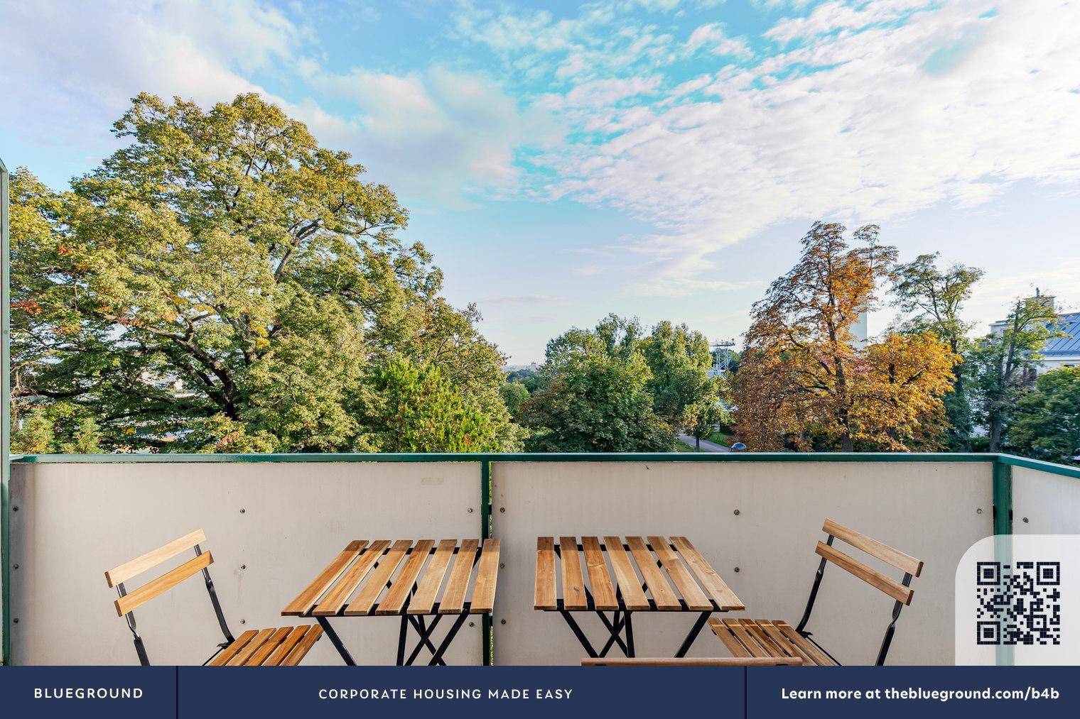 Balkon mit Holztisch und Stühlen bietet einen weiten Blick ins Grüne und auf die Umgebung.