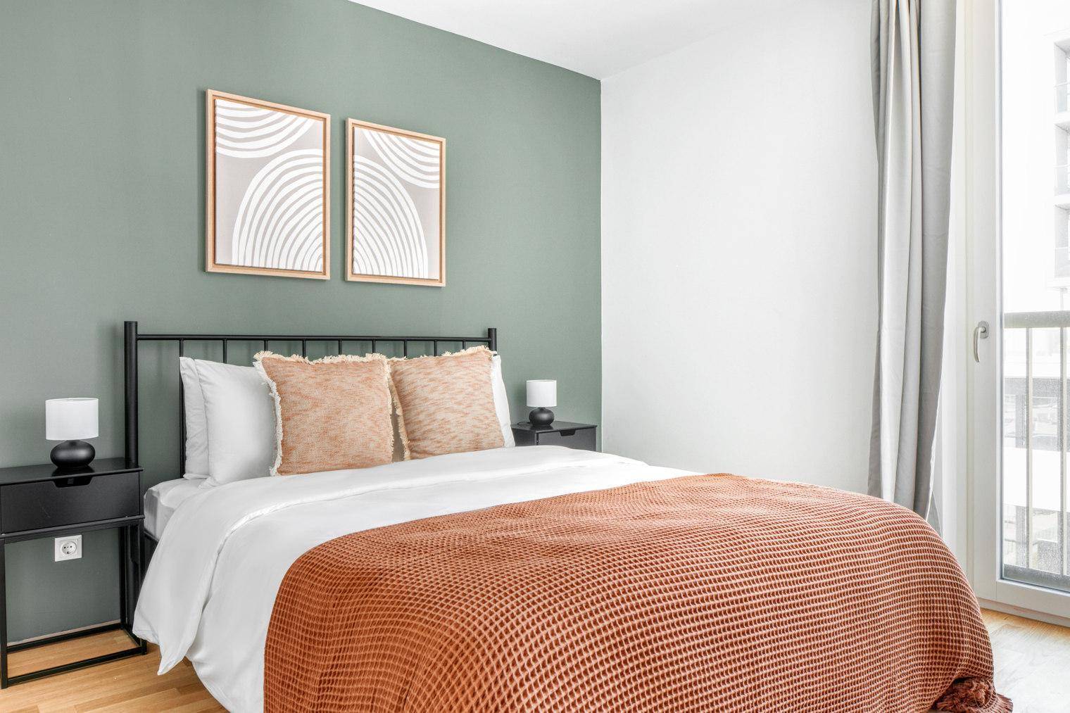 Gemütliches Schlafzimmer mit grün gestrichener Wand, Doppelbett und Holzboden.
