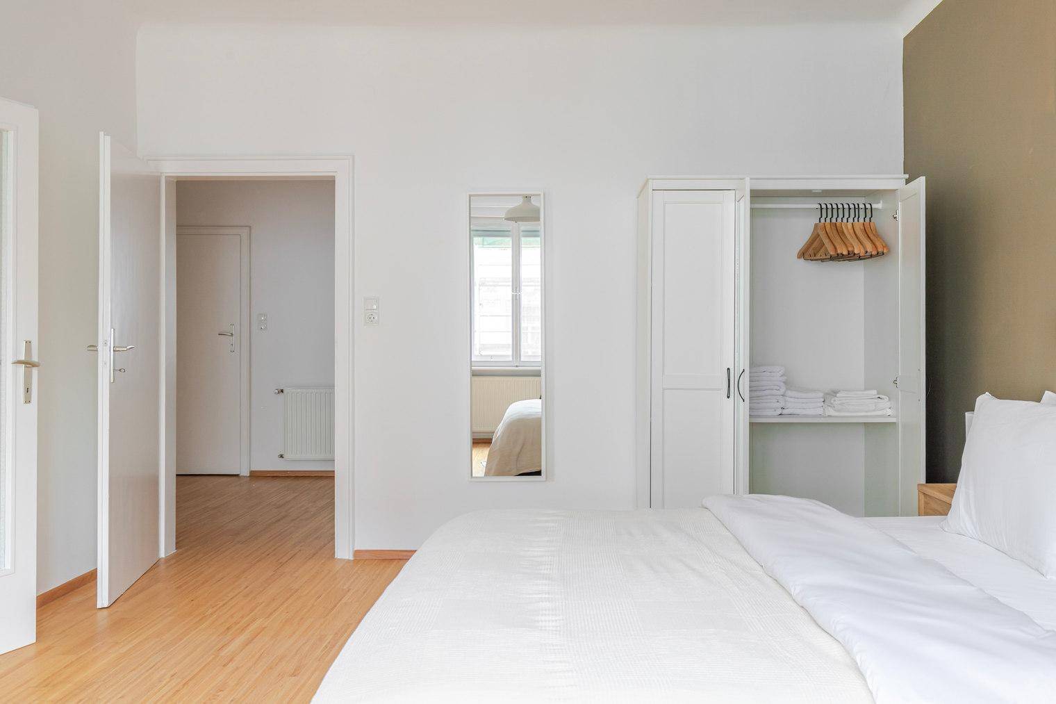 Schlafzimmer mit offenem Kleiderschrank und Zugang zu anderen Räumen.