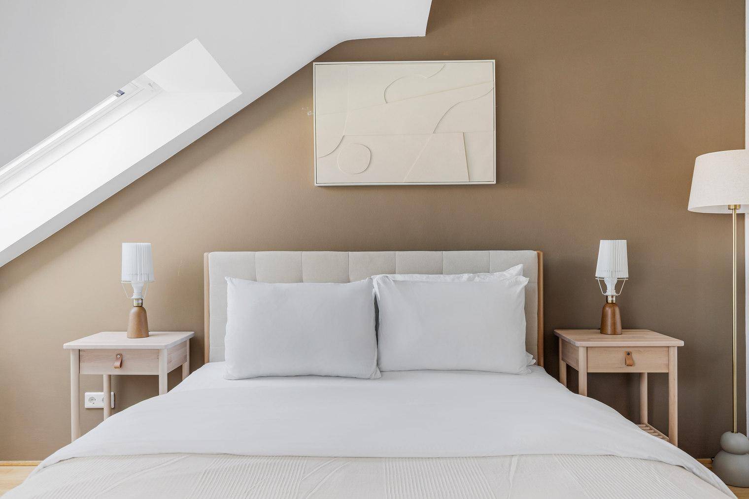 Komfortables Schlafzimmer im Dachgeschoss mit Doppelbett, Nachttischen und warmer Wandfarbe.