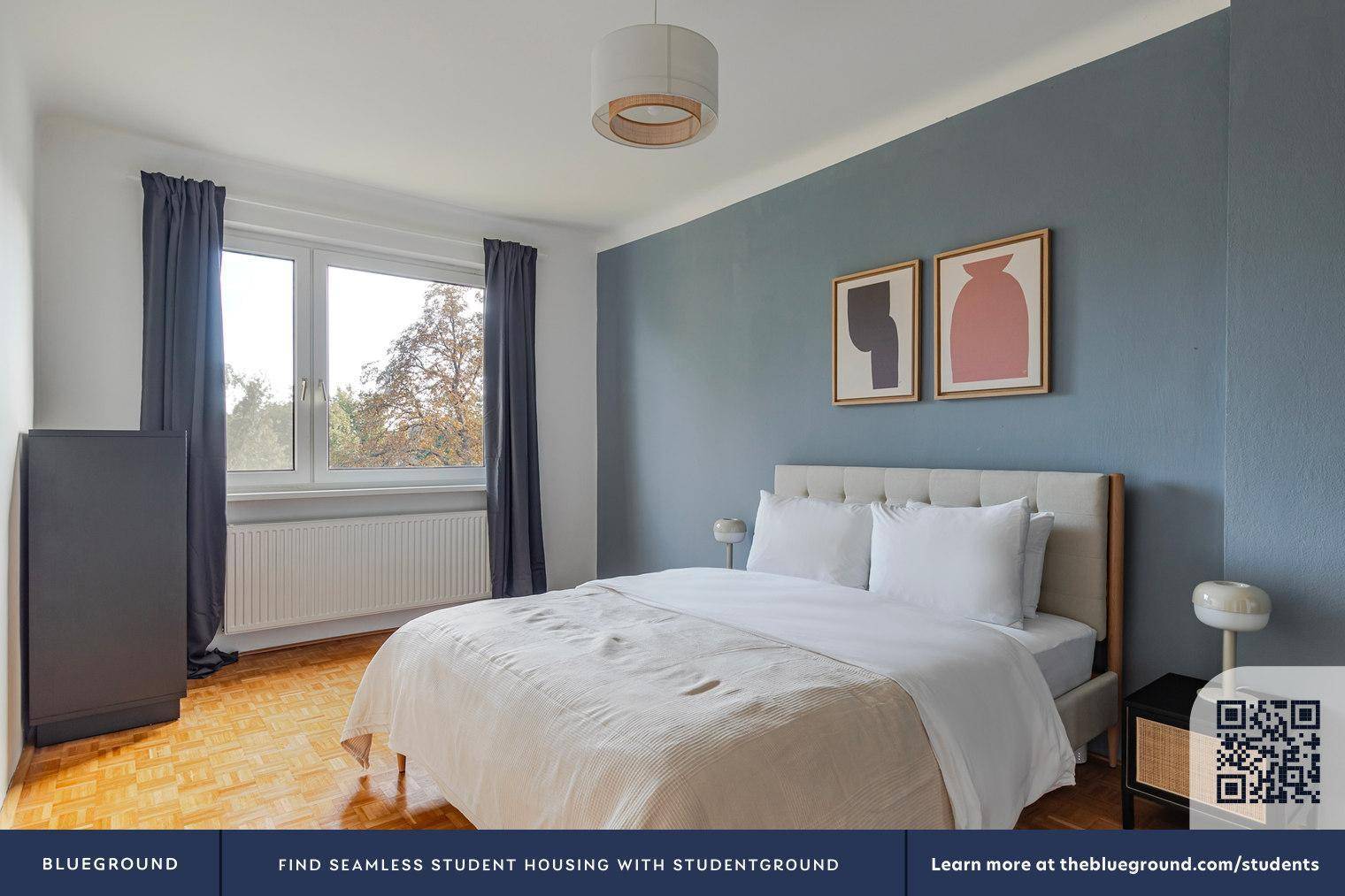 Gemütliches Schlafzimmer mit Doppelbett, Holzboden und einer blaugrauen Akzentwand.