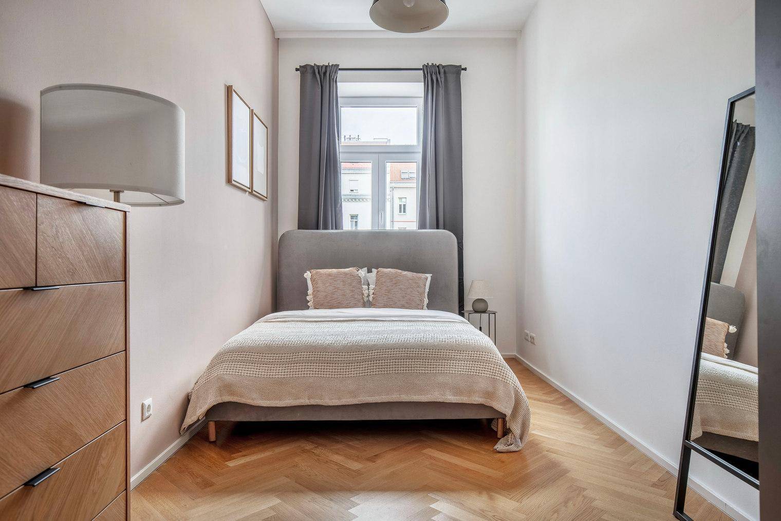 Gemütliches Schlafzimmer mit Doppelbett, Holzkommode und Fischgrätparkettboden.