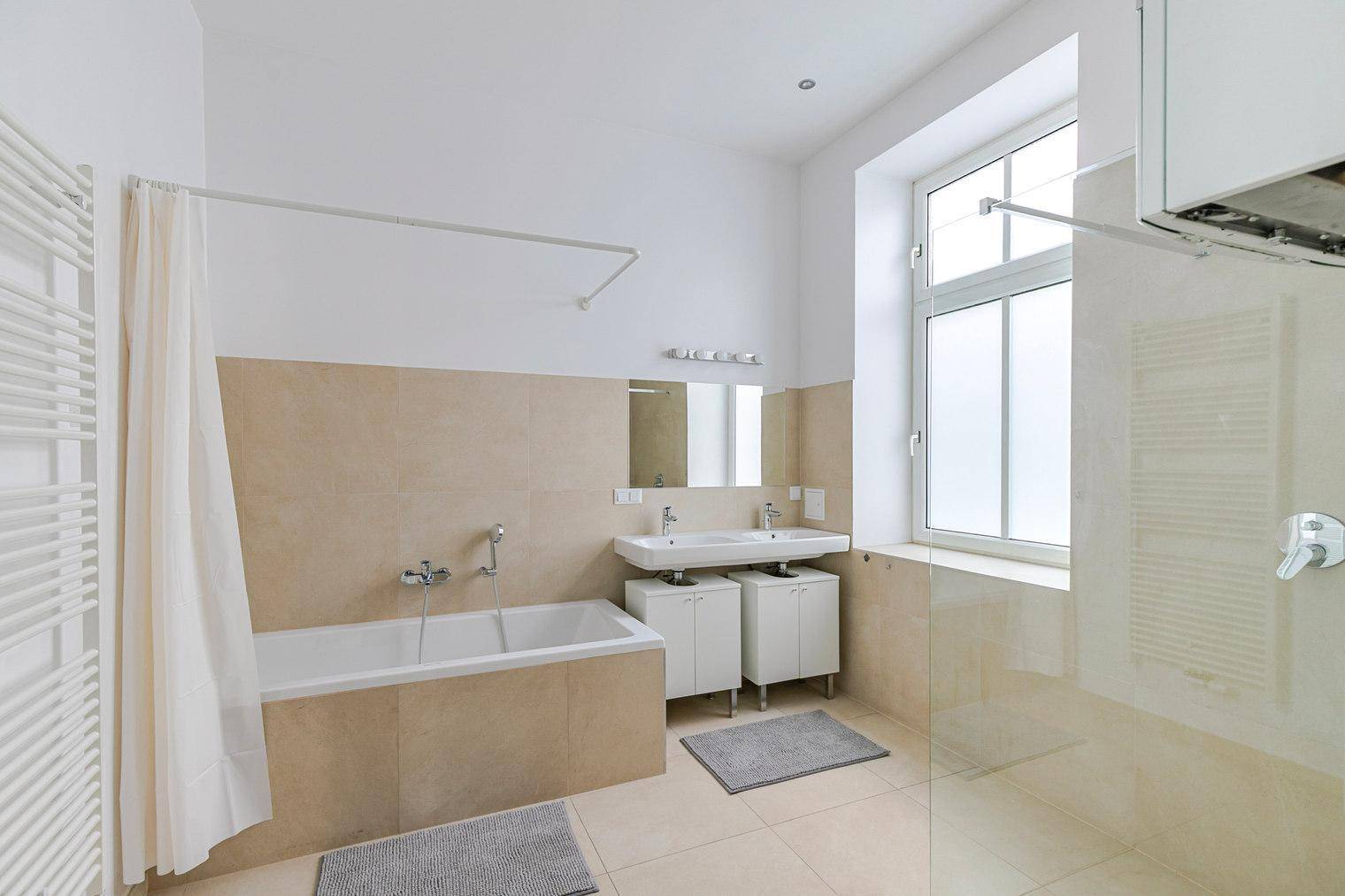 Geräumiges Badezimmer mit Badewanne, Dusche, Doppelwaschbecken und Fenster.