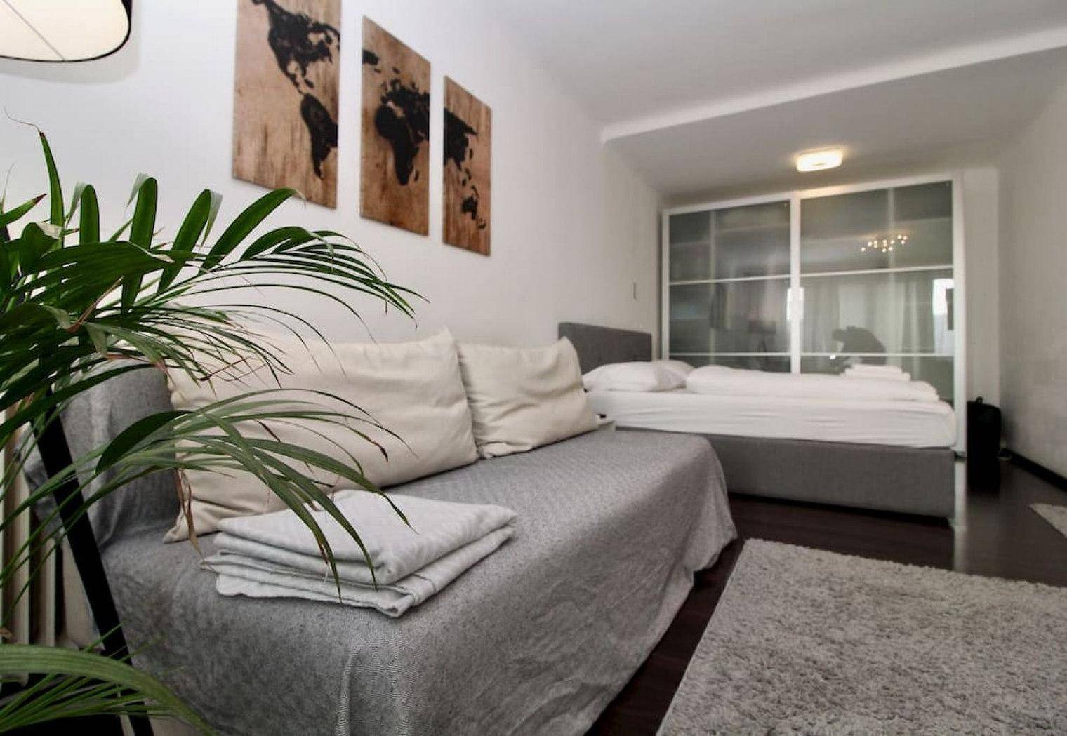 Gemütliches Sofa und Doppelbett in einem kombinierten Wohn- und Schlafbereich mit Schiebetürenschrank.