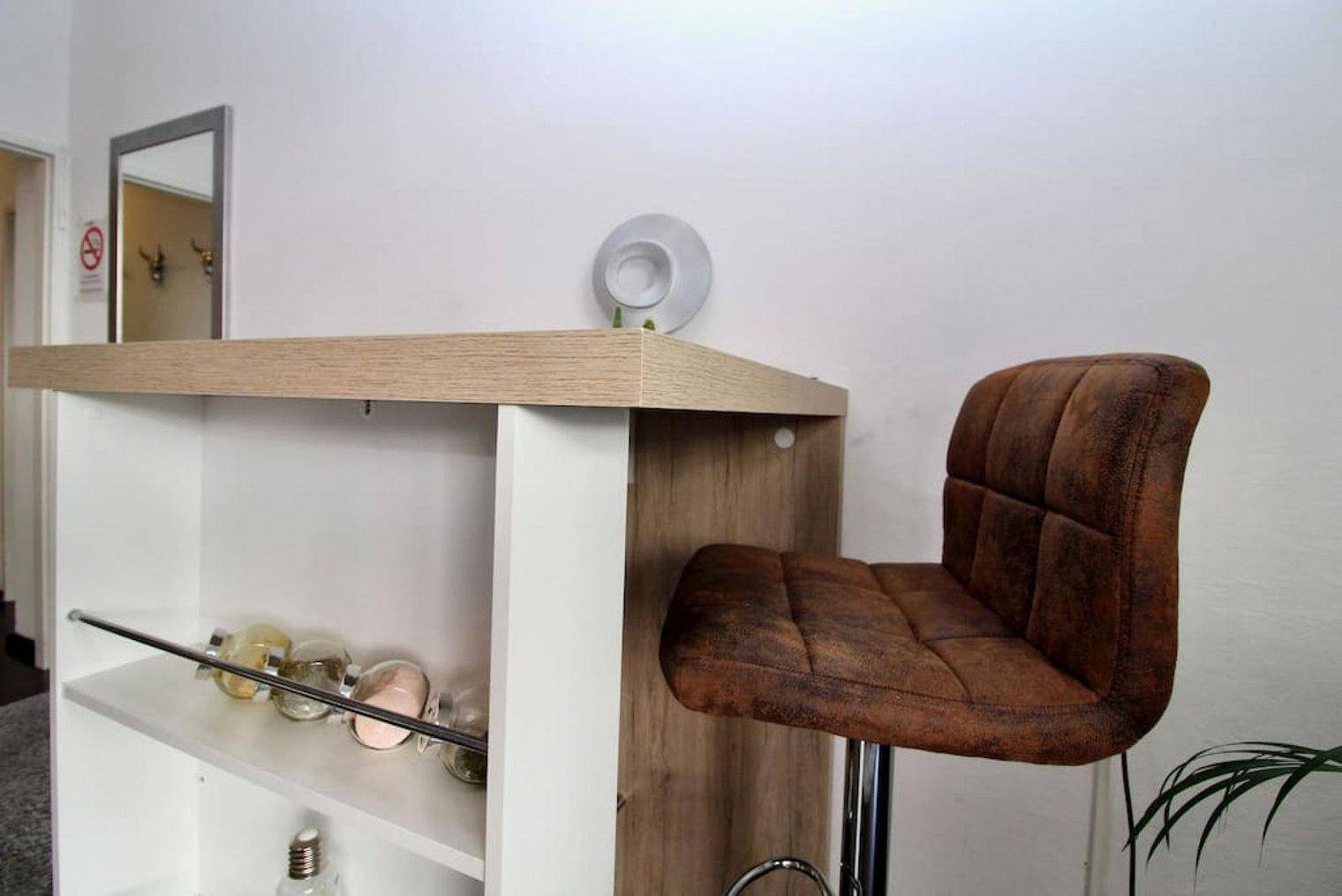 Moderner Bartisch mit Hocker und dekorativem Spiegel im Hintergrund.