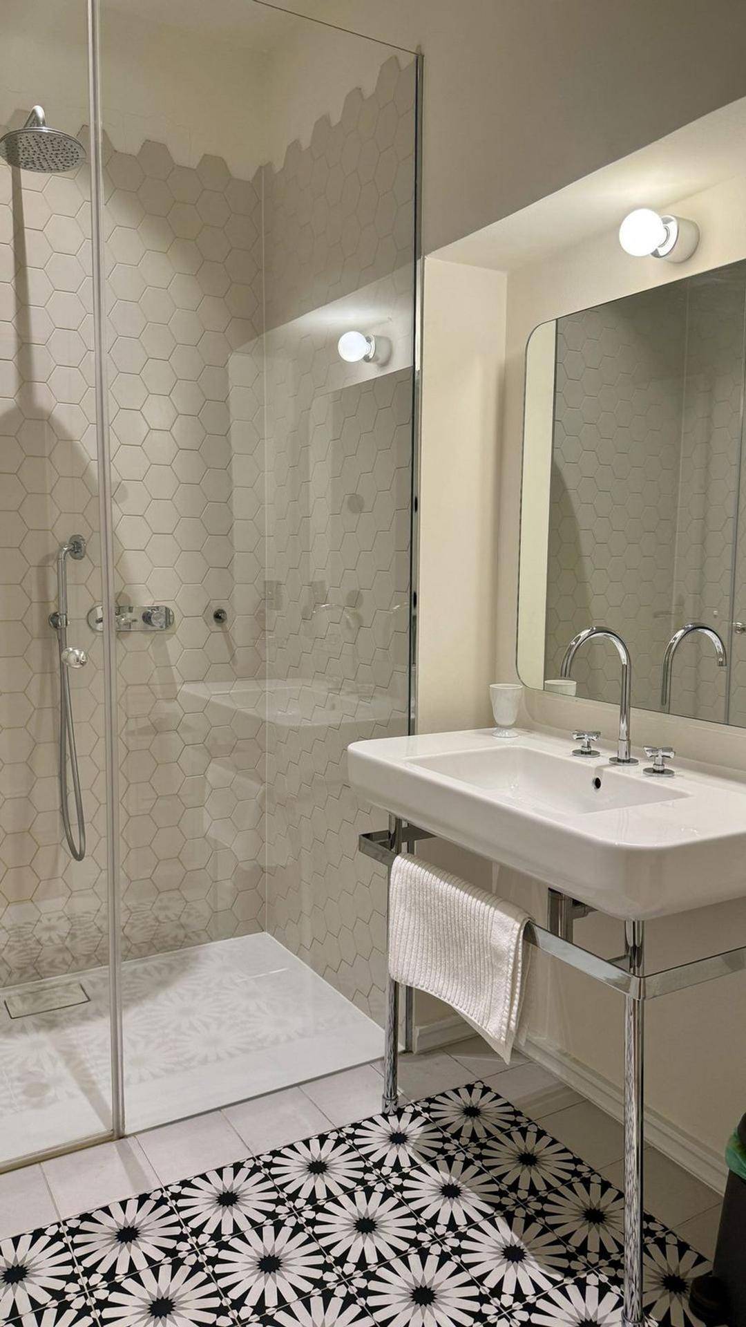 Modernes Badezimmer mit begehbarer Dusche, sechseckigen Fliesen und elegantem Waschbecken.