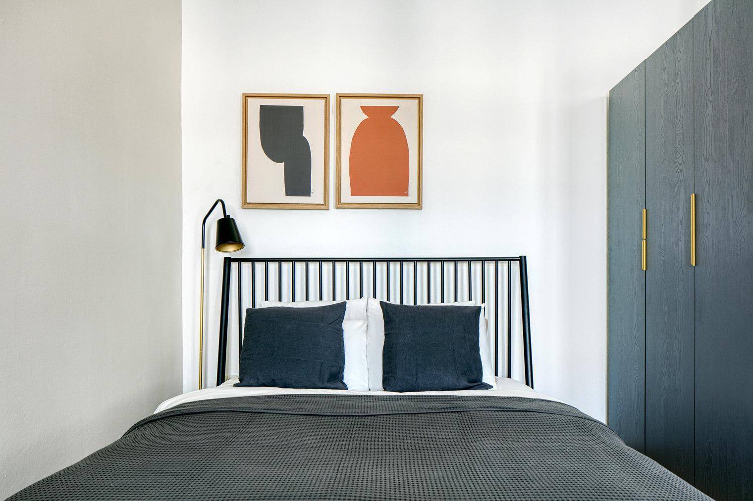 Schlafzimmer mit Doppelbett, dunklem Kopfteil und modernem Kleiderschrank.
