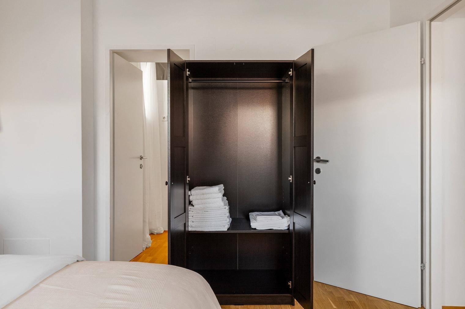 Offener Kleiderschrank im Schlafzimmer mit Stauraum für Kleidung und Handtücher.