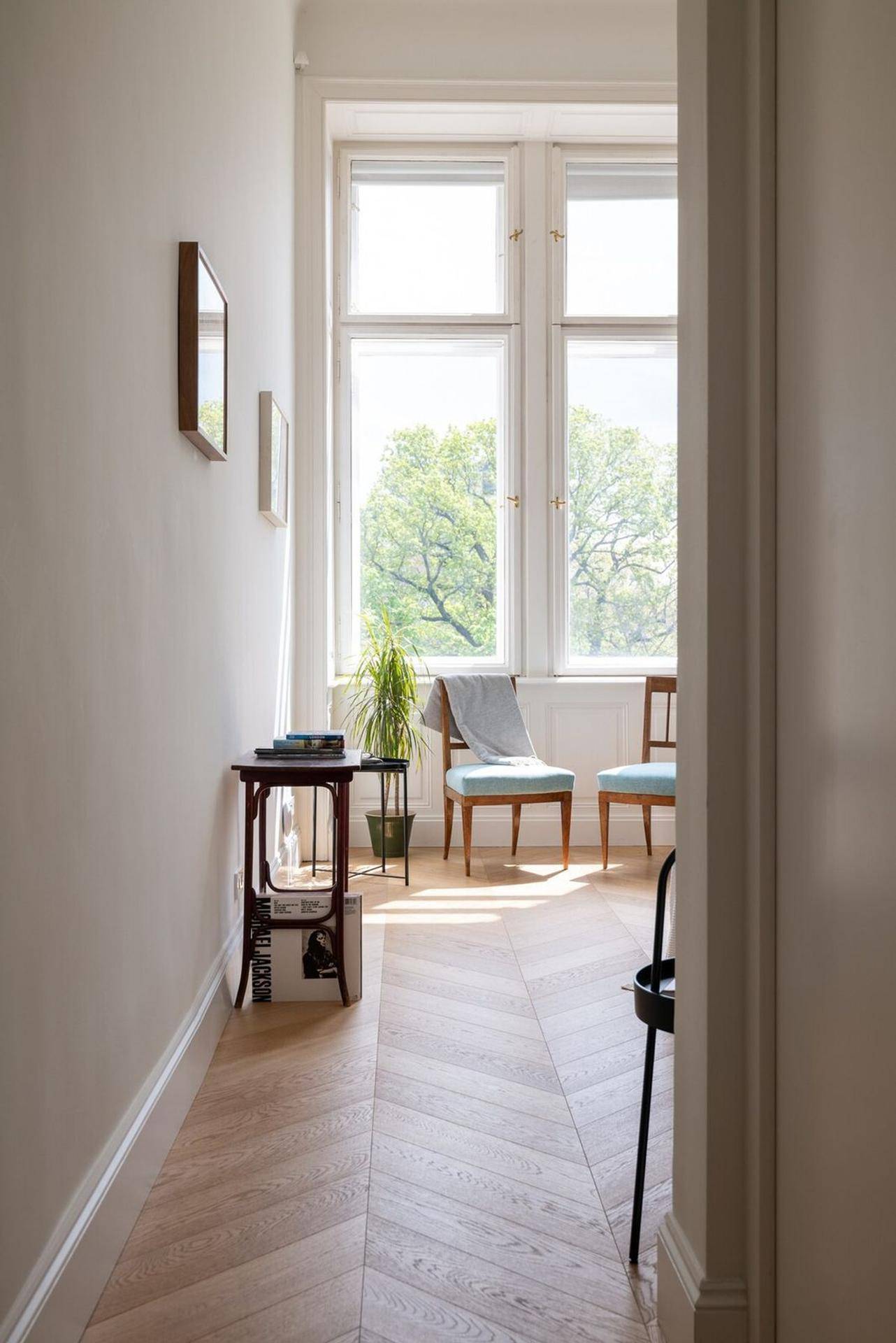 Heller Fensterbereich mit zwei Stühlen und einer Pflanze, die viel Tageslicht hereinlässt.