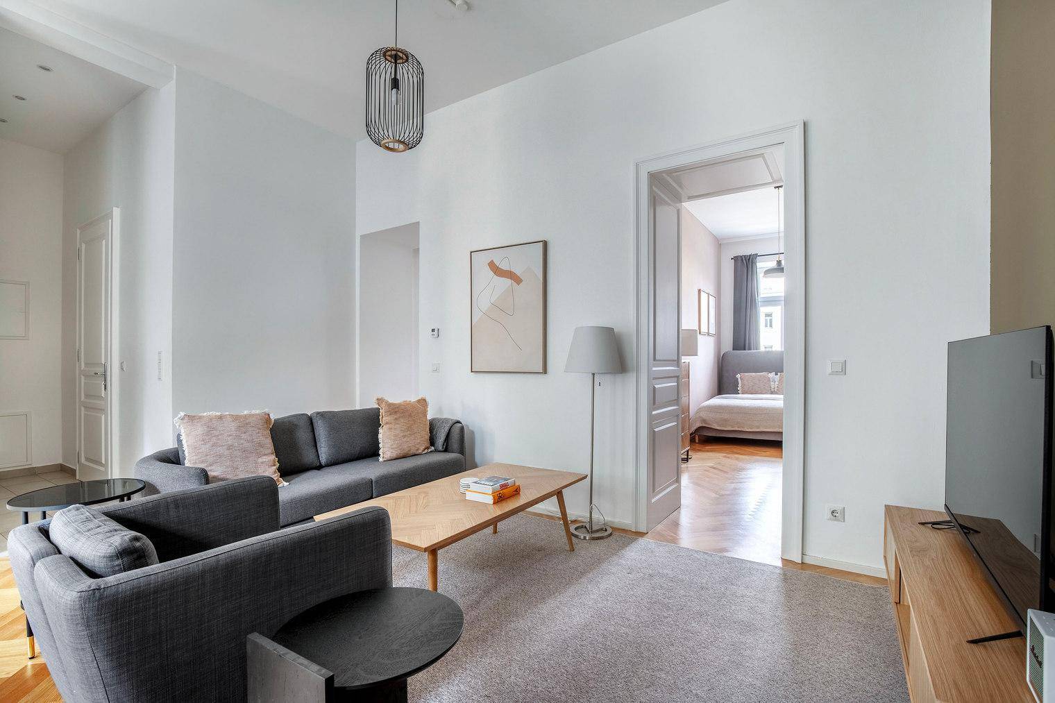Gemütliches Wohnzimmer mit Sofa, Couchtisch und Blick in ein angrenzendes Schlafzimmer.