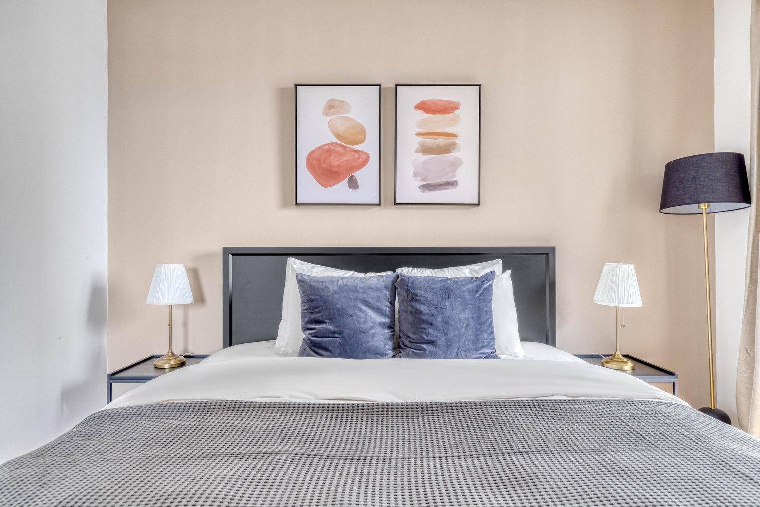 Gemütliches Schlafzimmer mit Doppelbett, blauen Kissen und moderner Wanddekoration.