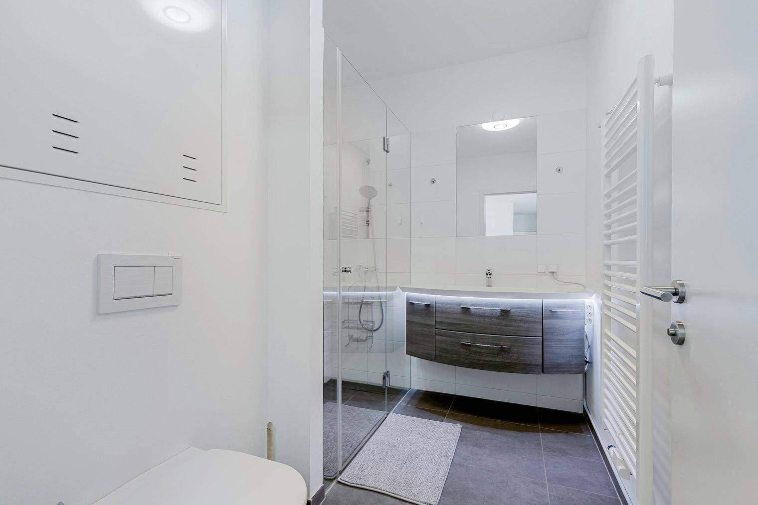 Modernes Badezimmer mit begehbarer Dusche, schwebendem Waschtisch und beheiztem Handtuchhalter.