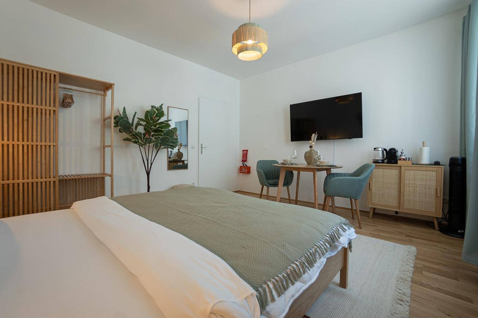 Schlafzimmer mit Doppelbett, Esstisch und an der Wand montiertem Fernseher für Komfort.