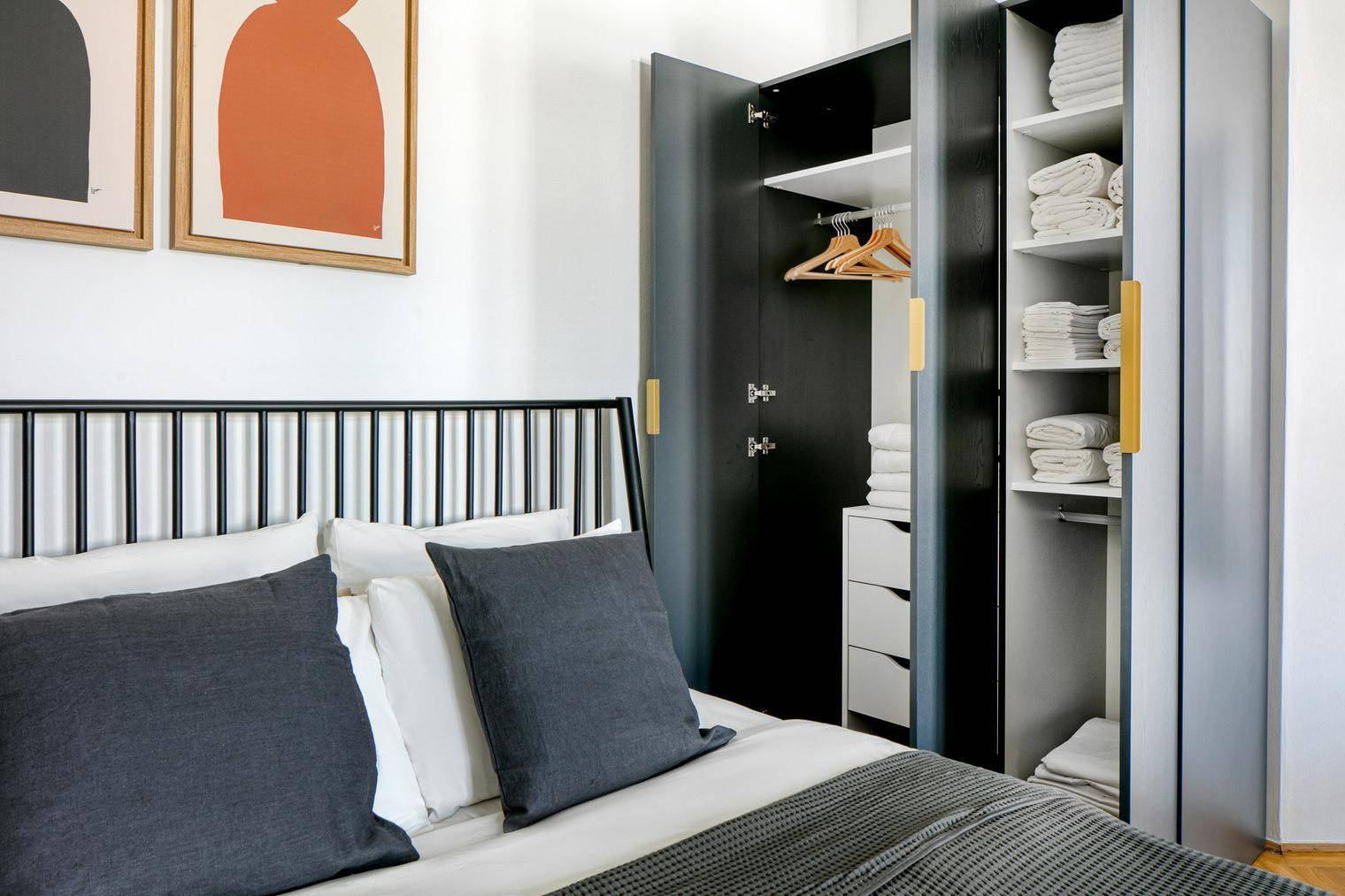 Offener Kleiderschrank im Schlafzimmer mit Regalen und Kleiderstange.