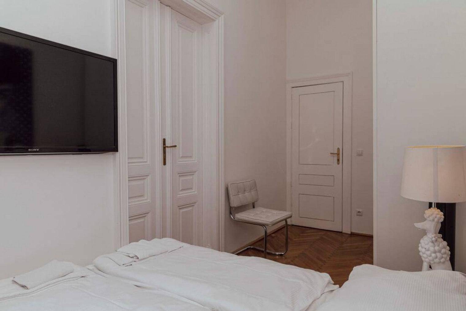 Schlafzimmer mit Doppelbett, weißer Bettwäsche und einer Nachttischlampe in Pudelform.