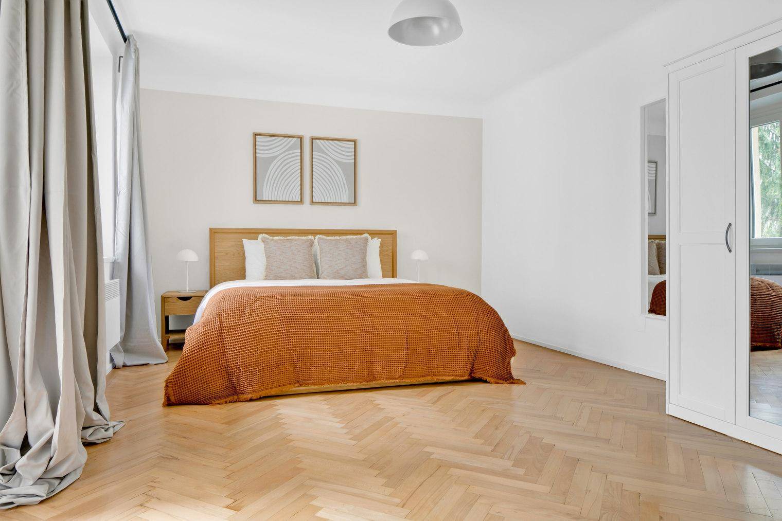 Geräumiges Schlafzimmer mit Holzboden, Doppelbett und weißem Kleiderschrank.